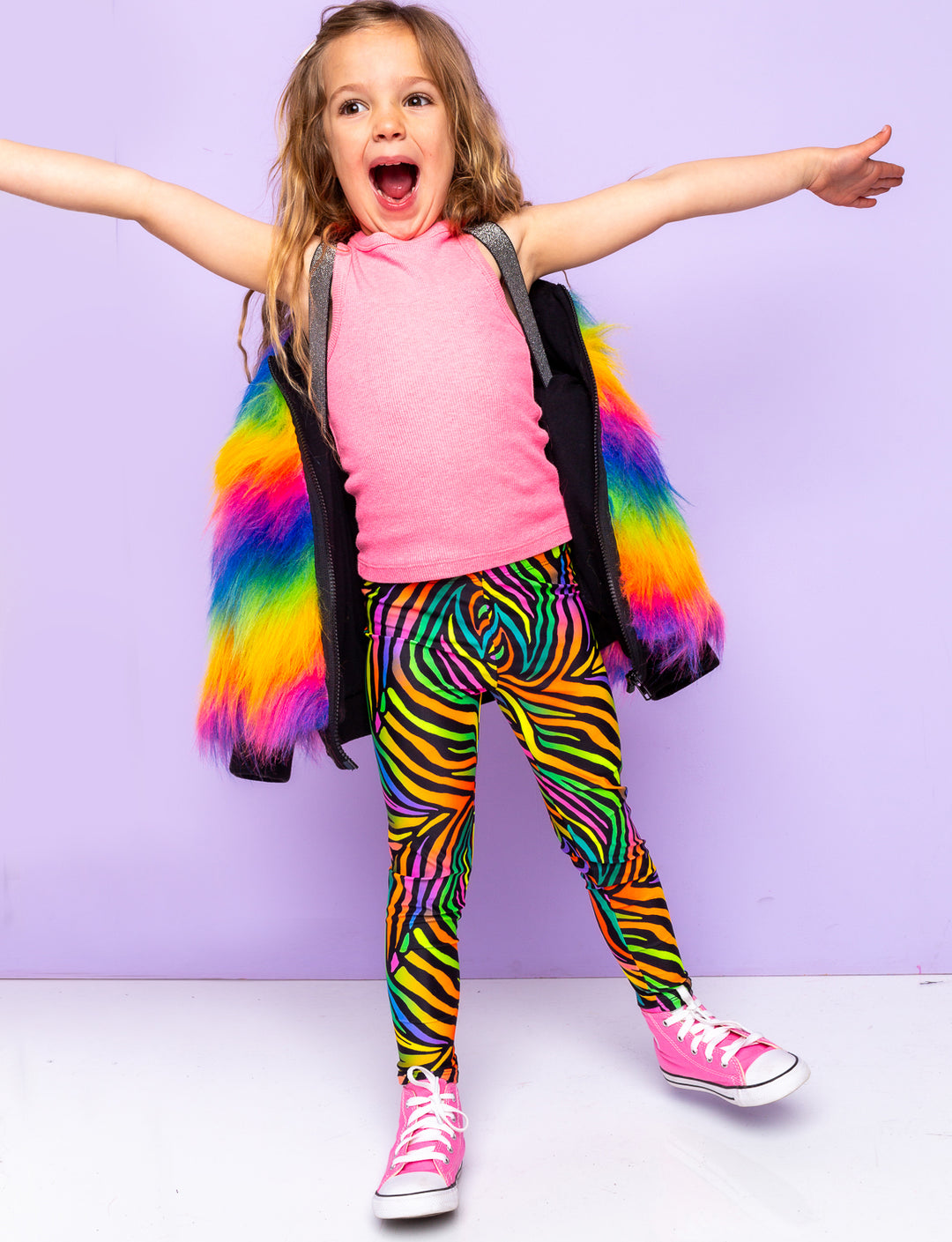 Girl modelling rainbow zebra print leggings with a rainbow fur jacket.