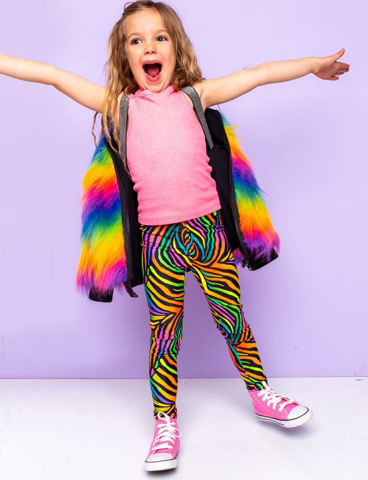 Girl modelling rainbow zebra print leggings with a rainbow fur jacket.