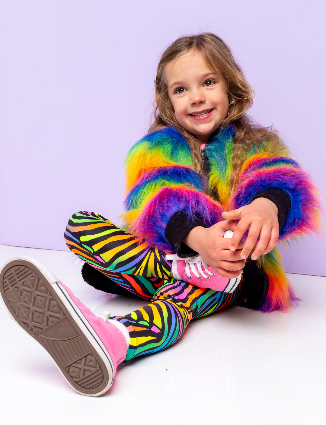 Girl modelling rainbow zebra print leggings with a rainbow fur jacket.