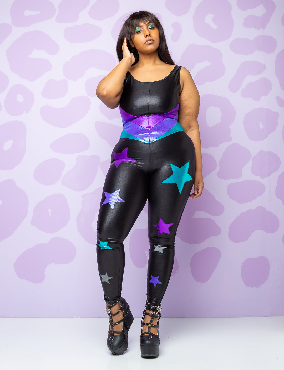 woman wearing black catsuit with purple and turquoise stars on the legs and panels on the body