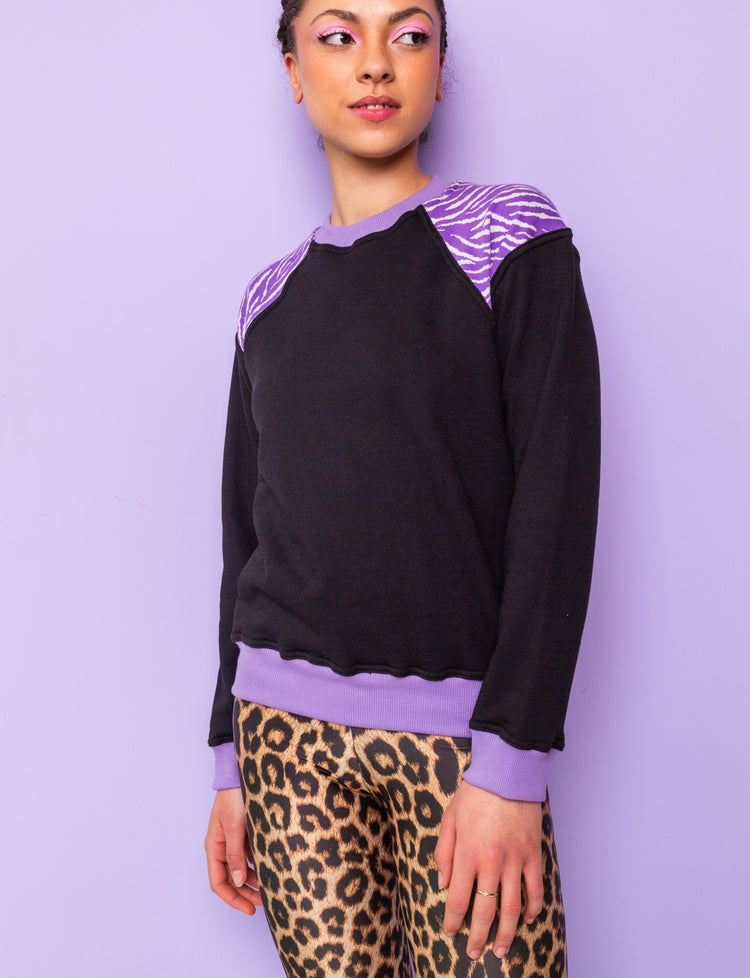 woman wearing a black sweatshirt with purple zebra print shoulders
