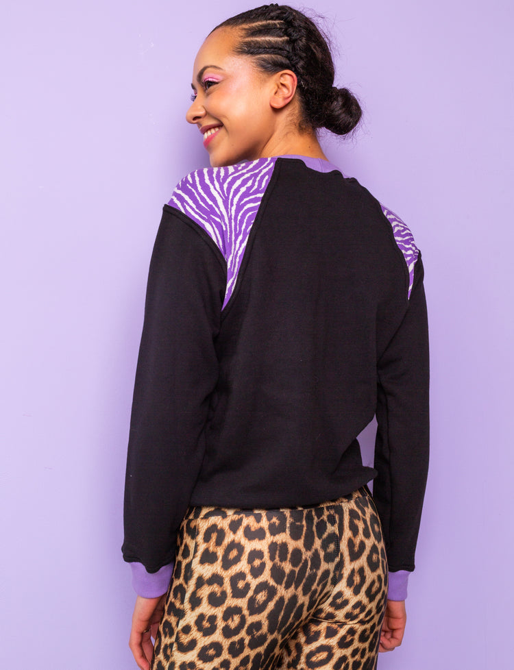 back view of a woman wearing a black sweatshirt with purple zebra print shoulders