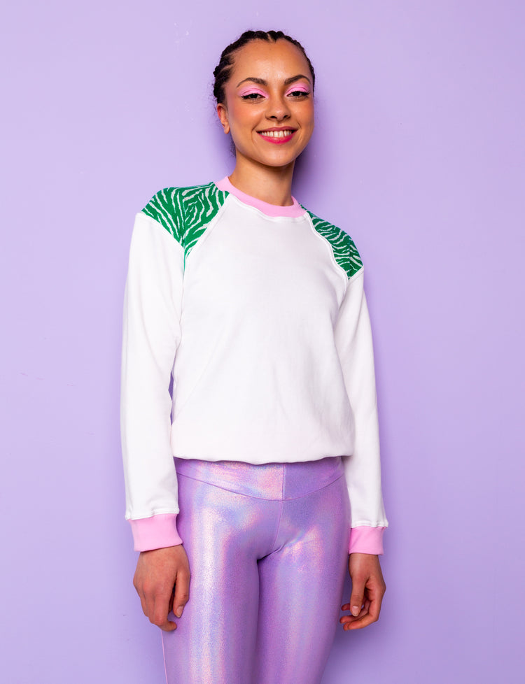 woman wearing a white sweatshirt with green zebra print shoulders tucked under at the hips